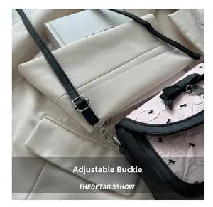Détail de la bandoulière réglable en cuir noir avec boucle argentée sur sac rose à nœuds