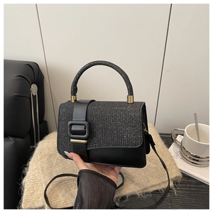 Détail du sac à rabat en cuir et paillettes noires avec boucle métallique carrée