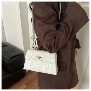 Gros plan d'un sac à main blanc à motif crocodile avec fermoir doré sur un modèle