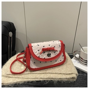 Détail du sac bandoulière rouge et blanc avec gaufrage floral et breloque cœur