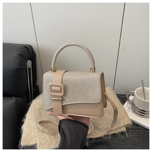 Détail d'un sac beige avec rabat pailleté et poignée métallique ronde élégante