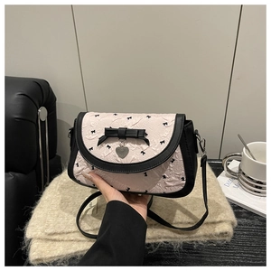 Détail d'un sac à main rose avec nœud, tissu plissé, motif floral et pendentif cœur