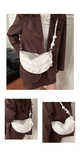 Detail view of white crescent bag showing knotted shoulder strap and glossy leather finish