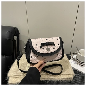 Détail du sac à bandoulière rose texturé avec nœuds noirs et pendentif en cœur