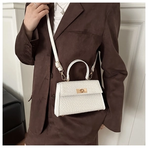 Détail d'un sac à main blanc motif crocodile avec fermoir doré et bandoulière en cuir