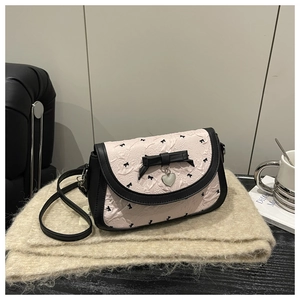 Détail du sac bandoulière rose plissé avec nœuds noirs et pendentif en cœur