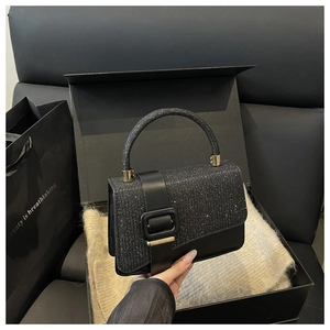 Détail d'un sac bandoulière noir scintillant présenté dans un coffret cadeau de luxe