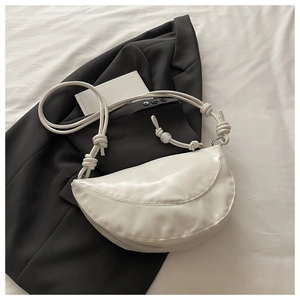Détail du sac dumpling blanc cassé avec cuir texturé et bandoulière à nœuds décoratifs