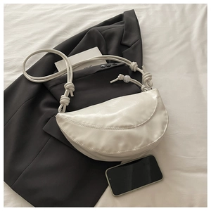 Détail du sac dumpling blanc cassé avec poignée nouée et perle sur costume noir