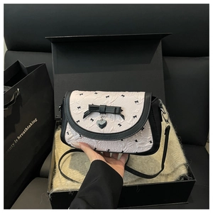 Détail du sac bandoulière noir et blanc avec nœud dans un coffret cadeau élégant