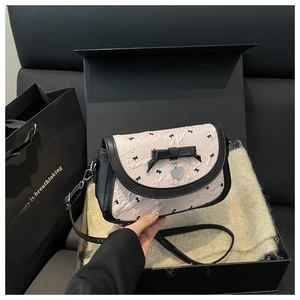 Détail du sac à bandoulière rose avec imprimés nœuds noirs dans un coffret cadeau