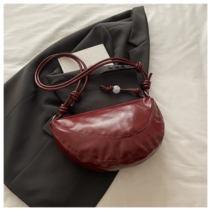 Détail du sac croissant bordeaux avec texture en cuir brillant et perles marbrées