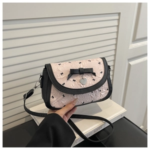 Détail du sac à bandoulière rose à nœuds avec pendentif cœur et sangle en cuir