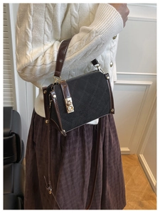 Detail of quilted suede texture and gold twist lock on contrast shoulder bag