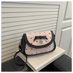 Détail du sac à bandoulière rose plissé à nœuds avec pendentif cœur argenté et bordure
