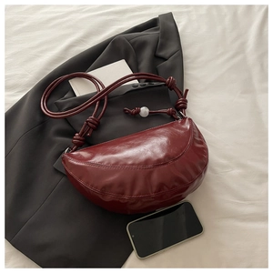Détail du sac demi-lune bordeaux avec finition brillante et perle blanche décorative