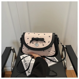 Détail du sac plissé rose avec nœuds noirs et pendentif en forme de cœur argenté
