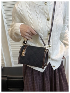 Detail of rhombic quilted crossbody bag with brown leather trim and gold twist lock clasp