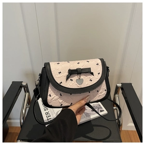 Détail du sac bandoulière rose plissé avec nœuds noirs et pendentif cœur argenté
