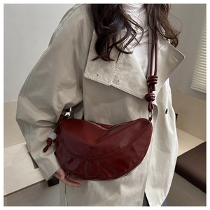 Détail d'un sac demi-lune bordeaux avec des nœuds décoratifs et texture cuir