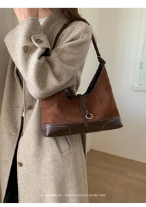 Detail of retro brown suede shoulder bag with contrast stitching and metal ring accent