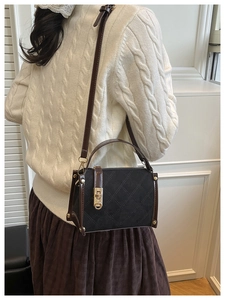 Detail of a vintage quilted crossbody bag with gold lock and brown accents on white sweater