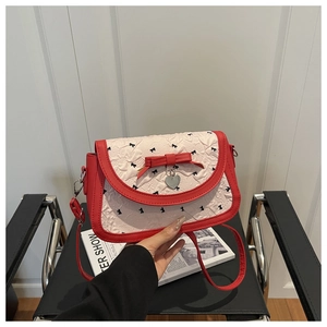 Détail du sac rouge avec tissu froncé crème, motifs de nœuds et pendentif en cœur
