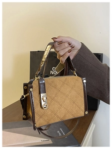 Detailed close-up of brown quilted handbag with a gold twist lock and metal rivet trim