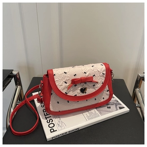 Détail du sac bandoulière jacquard rouge et blanc avec pendentif coeur et motifs nœuds