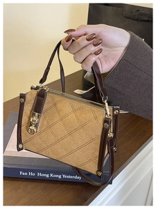 Detailed view of brown quilted crossbody bag with gold twist lock on a wooden table