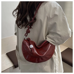Détail du sac croissant bordeaux avec bandoulière à nœud et perle blanche à l'épaule
