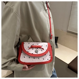 Détail d'un nœud rouge et pendentif cœur sur un sac à bandoulière blanc imprimé rubans