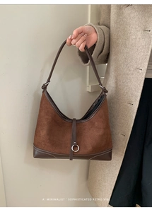 Detail of brown suede hobo bag with silver ring buckle shown on beige coat outfit