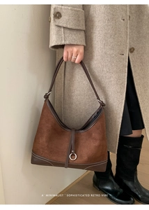 Detail of caramel suede tote with contrast white stitching and silver metal ring hardware