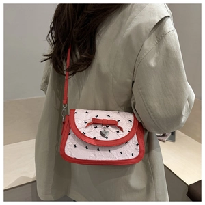 Détail du sac bandoulière blanc plissé avec nœuds rouges et pendentif cœur sur modèle