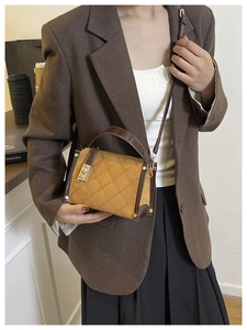 Close-up of brown quilted faux suede handbag with vintage metal twist lock and stitching