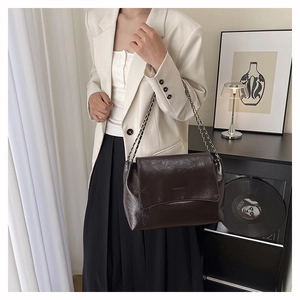 Vue détaillée de la texture du cuir ciré marron foncé et de la chaîne d'un sac vintage