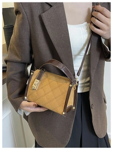 Detail of quilted leather crossbody bag featuring vintage gold clasp and brown strap