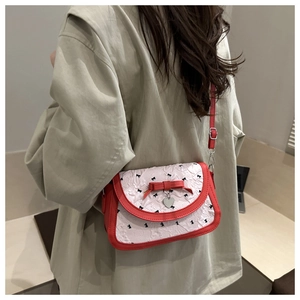 Détail du nœud rouge et pendentif cœur sur le sac à bandoulière imprimé
