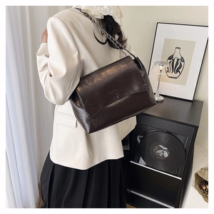 Close-up of brown oiled leather shoulder bag with vintage silver chain on a rack