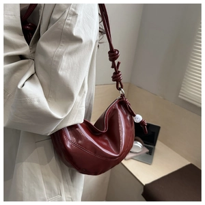 Détail du sac lune bordeaux avec texture en cuir et bandoulière à nœud distinctive