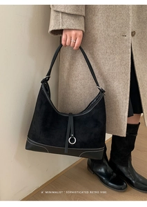 Detail of black suede tote bag with leather trim and white contrast stitching detail
