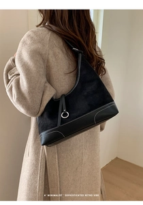 Detail of black suede hobo bag with contrast stitching and silver metal ring accessory