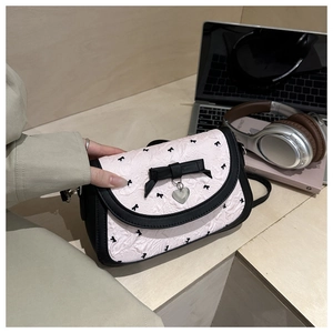 Détail du sac à bandoulière rose à nœuds avec tissu plissé et pendentif cœur argenté