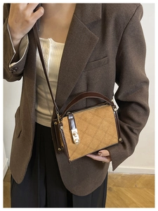 Detail of small brown crossbody bag featuring quilted patterns and a gold twist-lock closure