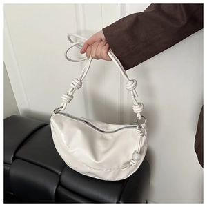 Détail d'un sac demi-lune blanc avec bandoulière nouée et boucles en métal argenté