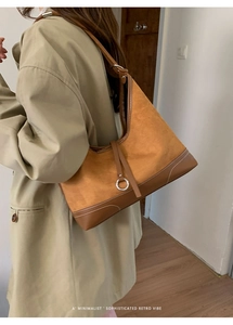Detail of retro suede and leather patchwork tote with white stitching and silver hardware