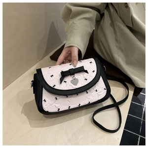 Détail du sac bandoulière rose plissé avec nœuds noirs et pendentif cœur argenté