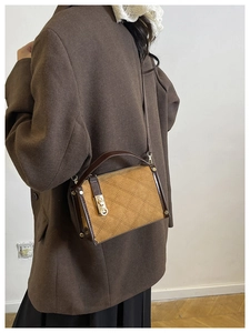 Detail of vintage crossbody bag showing quilted brown suede and leather texture on a model