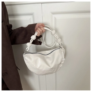 Détail du sac dumpling blanc avec bandoulière à nœuds et texture en cuir PU lisse